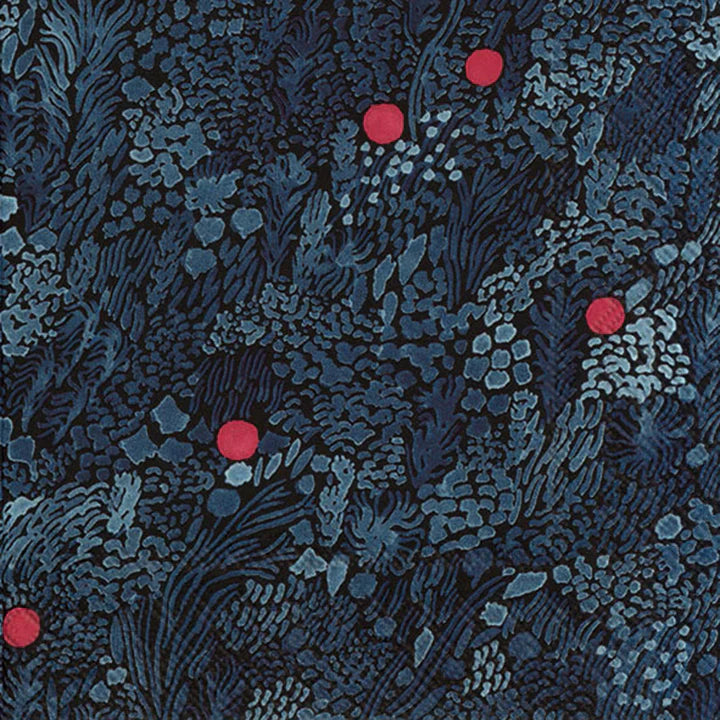 A close-up image of a patterned Marimekko cocktail napkin featuring floral designs with red accents on a dark blue background.