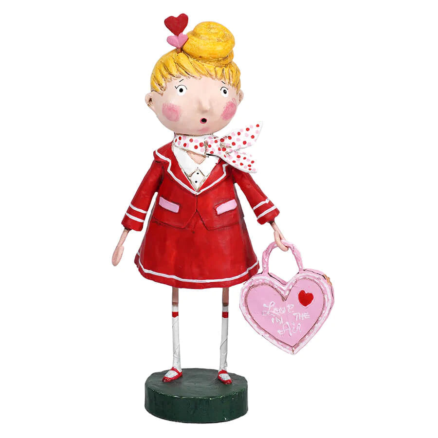 A whimsical resin figurine of a red-dressed 'Love is in the Air' flight attendant with a polka-dotted scarf and holding a heart-shaped sign.