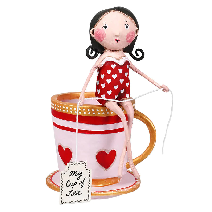 A resin figurine of a woman in a red swimsuit with white hearts, sitting on a large teacup with hearts, holding a cup with the text 'my cup of tea'.