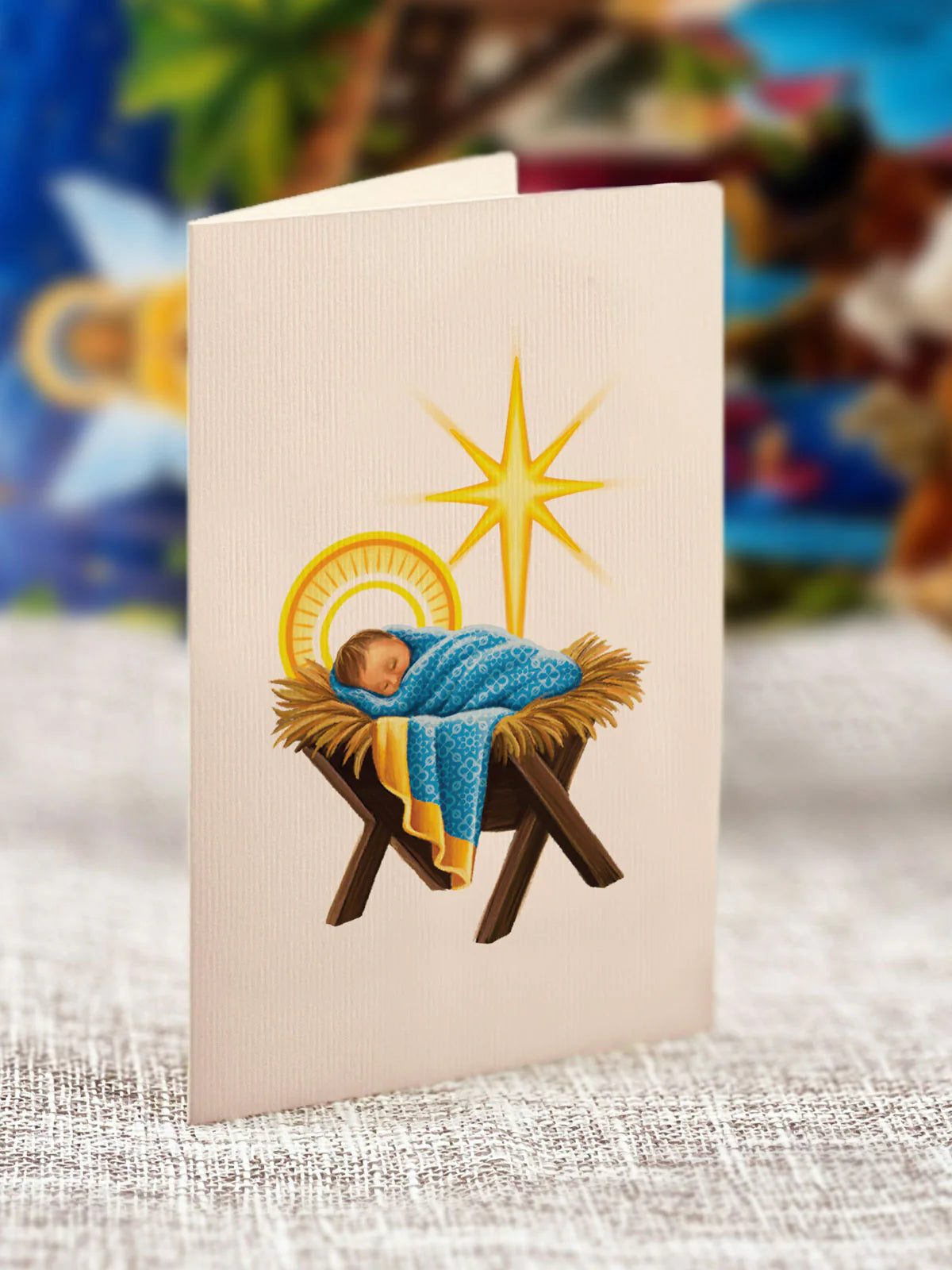 Image shows the included matching notecard for the Starlit Nativity pop-up Christas decor from FreshCut Paper. The cover of the notecard shows the baby Jesus asleep in a cradle while a large yellow star is shown above