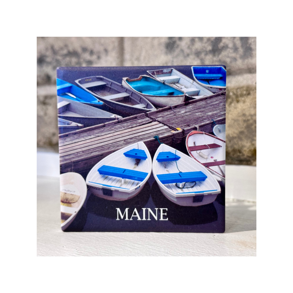 A ceramic coaster showing rowboats tied to a dock in Perkins Cove located in Ogunquit, Maine, a photo taken by David Sullivan of D. Sullivan Photography.
