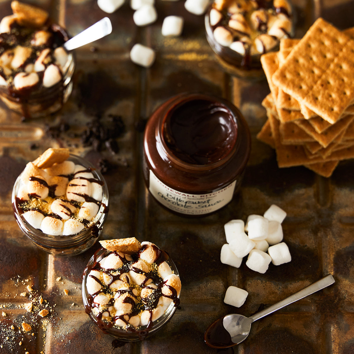 open jar of bittersweet chocolate sauce with marshmallows and graham crackers s&#39;mores in mason jars